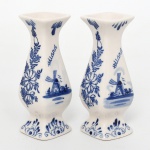 Par de pequenos vasos em porcelana, esmaltação branca, bojo de perfil balaústre, borda levemente evertida. Decoração em azul sob vidrado, aplicada manualmente, com motivos florais estilizados e representação de moinho de vento em paisagem. Inscrição Holland. Base com marca manuscrita Hand Painted Delft Blue Colour. Medidas: Alt.: 11 x Comp.: 4 x Larg.: 4 cm.