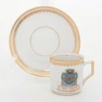 Porcellana Mauá, Mauá - SP(Fundada em 1937 por Fritz Erwin Schmidt / ativa até 1968). Elegante xícara de coleção, para café, em porcelana nacional da década de 1960; comemorativa do IV CENTENÁRIO DO RIO DE JANEIRO 1565 - 1965, bojo cilíndrico e asa lateral estilizada, decoração com filetes dourados na borda e na base, friso ornamental na aba e brasão da cidade do Rio de Janeiro aplicado em estampagem policromada na face da xícara. Inscrição comemorativa IV Centenário  1565  Rio de Janeiro 1965 em douração. Item produzido por ocasião das comemorações do quarto centenário da fundação da cidade do Rio de Janeiro, evento celebrado em 1965. Marca da manufatura no verso. Medidas: Xícara: Alt.: 5 x Comp.: 6,5 x Larg.: 5 cm; Pires: Diam.: 10,5 cm. Apresenta acentuada trinca na face frontal da xícara.