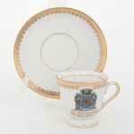 Porcellana Mauá, Mauá - SP(Fundada em 1937 por Fritz Erwin Schmidt / ativa até 1968). Elegante xícara de coleção, para café, em porcelana nacional da década de 1960; comemorativa do IV CENTENÁRIO DO RIO DE JANEIRO 1565 - 1965, bojo campanular com pé anelar e asa lateral em voluta, decoração com filetes dourados na borda e no pé, friso ornamental na aba e brasão da cidade do Rio de Janeiro aplicado em estampagem policromada na face da xícara. Inscrição comemorativa IV Centenário  1565  Rio de Janeiro  1965 em douração. Item produzido por ocasião das comemorações do quarto centenário da fundação da cidade do Rio de Janeiro, evento celebrado em 1965. Marca da manufatura no verso. Medidas: Xícara: Alt.: 5 x Comp.: 7 x Larg.: 5,5 cm; Pires: Diam.: 10,5 cm.