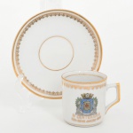 Porcellana Mauá, Mauá - SP(Fundada em 1937 por Fritz Erwin Schmidt / ativa até 1968). Elegante xícara de coleção, para café, em porcelana nacional da década de 1960; comemorativa do IV CENTENÁRIO DO RIO DE JANEIRO 1565 - 1965, bojo cilíndrico e asa lateral estilizada, decoração com filetes dourados na borda e na base, friso ornamental na aba e brasão da cidade do Rio de Janeiro aplicado em estampagem policromada na face da xícara. Inscrição comemorativa IV Centenário 1565 Rio de Janeiro 1965 em douração. Item produzido por ocasião das comemorações do quarto centenário da fundação da cidade do Rio de Janeiro, evento celebrado em 1965. Marca da manufatura no verso. Medidas: Xícara: Alt.: 5 x Comp.: 6,5 x Larg.: 5 cm; Pires: Diam.: 10,5 cm.
