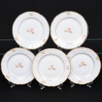 Porcelana Rio Branco/Cia. Brasileira de Vidros, Rio de Janeiro - RJ(Fundada em 1947, ativa até 1967). Conjunto de pratos para sobremesa em porcelana nacional da década de 1950; esmaltagem vítrea na cor branca, dotada de decoração em estampagem policromada, com padrão de flores predominando as tonalidades rosa, amarelo, castanho e cinza, aba circundada com leve movimento ondulatório modelado na própria pasta, borda recortada contornada por friso em douradura. Marca da manufatura no verso. Composto de cinco(05) unidades. Medida: Diam.: 19 cm. Apresentam marcas de uso, vide foto.
