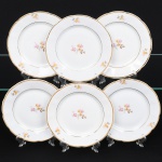 Porcelana Rio Branco/Cia. Brasileira de Vidros, Rio de Janeiro - RJ(Fundada em 1947, ativa até 1967). Conjunto de pratos para sobremesa em porcelana nacional da década de 1950; esmaltagem vítrea na cor branca, dotada de decoração em estampagem policromada, com padrão de flores predominando as tonalidades rosa, amarelo, castanho e cinza, aba circundada com leve movimento ondulatório modelado na própria pasta, borda recortada contornada por friso em douradura. Marca da manufatura no verso. Composto de seis(06) unidades. Medida: Diam.: 19 cm. Apresentam marcas de uso, vide foto.