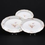 Porcelana Rio Branco/Cia. Brasileira de Vidros, Rio de Janeiro - RJ(Fundada em 1947, ativa até 1967). Três(03) travessas rasas de formato oval em porcelana nacional da década de 1950; esmaltagem vítrea na cor branca, dotada de decoração em estampagem policromada, com padrão de flores predominando as tonalidades rosa, amarelo, castanho e cinza, aba circundada com leve movimento ondulatório modelado na própria pasta, borda recortada contornada por friso em douradura. Marca da manufatura no verso. Medidas: Comp.: 29 x Larg.: 18,5 cm; Comp.: 34,5 x Larg.: 22 cm; Comp.: 38,5 x Larg.: 25 cm. Apresentam marcas de uso, uma com desgaste parcial na douradura da borda, e uma com bicado na borda, vide foto.