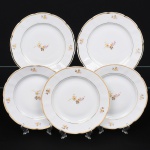 Porcelana Rio Branco/Cia. Brasileira de Vidros, Rio de Janeiro - RJ(Fundada em 1947, ativa até 1967). Conjunto de pratos rasos em porcelana nacional da década de 1950; esmaltagem vítrea na cor branca, dotada de decoração em estampagem policromada, com padrão de flores predominando as tonalidades rosa, amarelo, castanho e cinza, aba circundada com leve movimento ondulatório modelado na própria pasta, borda recortada contornada por friso em douradura. Marca da manufatura no verso. Composto de cinco(05) unidades. Medida: Diam.: 24 cm. Apresentam marcas de uso, vide foto.