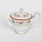 NORITAKE, Nagoya - Japão(Fundada em 1904 pelos irmãos Ichizaemon e Toyo Morimura). Exuberante bule para chá executado em porcelana japonesa, esmaltagem vítrea na cor branca, circundado por buquês de flores em estampagem policromada sobre faixa levemente em tom marfim, dotada de profusa ornamentação em douradura, com frisos, arabescos, e elementos vegetalistas sobrepondo faixa de tonalidade bordô contornando a borda, tampa encimada por puxador modelado em forma de fruto, bico curvilíneo de ponta recortada, alça lateral em grande voluta. Marca da manufatura ao fundo. Med.: Alt. 17,5 x Comp. 25,5 x Larg. 14,5 cm. Apresenta leves desgastes na douradura, vide foto.