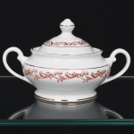 Porcelana Rio Branco/Cia. Brasileira de Vidros, Rio de Janeiro - RJ(Fundada em 1947, ativa até 1967). Elegante açucareiro executado em porcelana nacional da década de 1950/50, executado ao estilo francês do período Luís XV; esmaltagem vítrea na cor branca, decoração em esmalte vermelho-coral, formada por arabescos e ramos vegetalistas estilizados, realçada com filetes em douradura; corpo de perfil balaústre assentado sobre base circular, boca ligeiramente revirada para fora, alças laterais em voluta, tampa campaniforme encimada por puxador ovoide. Marca da manufatura no verso. Medidas: Alt.: 10,5 x Comp.: 17 x Larg.: 12 cm.