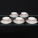 Porcelana Rio Branco/Cia. Brasileira de Vidros, Rio de Janeiro - RJ(Fundada em 1947, ativa até 1967). Elegante conjunto de xícaras para chá em porcelana nacional da década de 1950/50;  esmaltagem vítrea na cor branca, bojo hemisférico com alça lçateral em voluta, decoração em esmalte vermelho-coral, formada por arabescos e ramos vegetalistas estilizados, dispostas ao redor do bojo e da orla o pires, realçada com filetes em douradura. Marca da manufatura no verso. Composto de cinco(05) unidades. Medidas: Xícara: Alt.: 4 x Comp.: 8,5 x Larg.: 7 cm; Pires: Diam.: 10,5 cm.