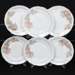 Porcelana Real, Mauá - SP(Fundada em 1943 por Fritz Erwin Schmidt). Conjunto de pratos rasos em porcelana nacional, esmaltação na cor branca, decoração com arranjos florais em tonalidades suaves de rosa, acompanhadas por folhas em verde claro, dispostos lateralmente na aba, complementado por filetes dourados finos aplicados próximos à borda e na linha interna da aba. Marca da manufatura no verso. Composto de seis(06) unidades. Medida: Diam.: 19 cm.