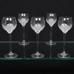 Conjunto taças de pé alto, para vinho do Porto, executadas em fino cristal europeu, diáfano e incolor; bojo globular, fundo preenchido e talhado com flor acetinada, fuste tubular alongado sobre base circular. Composto de cinco(05) unidades. Medidas: Alt.: 16,5 x 6 cm;