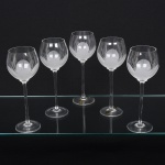 Belíssimo conjunto de taças de pé alto, para água, executado em fino cristal europeu, diáfano e incolor; bojo globular, fundo preenchido e talhado com flor acetinada, fuste tubular alongado sobre base circular. Composto de cinco(05) unidades. Medida: Alt.: 21,5 x Diam.: 8 cm.