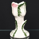 Vaso em cerâmica moldada, corpo vertical com base alargada e colo estreito, terminando em boca recortada em forma de flor. Estrutura modelada em relevo simulando folhas sobrepostas, com nervuras marcadas. Decoração em esmalte policromo, com folhas em tons de verde e detalhes em rosa nas extremidades, sobre fundo branco. Medidas: