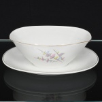 Porcelana Renner, Porto Alegre - RS(Fundada em 1937). Elegante molheira em porcelana nacional, bojo oblongo, de interior côncavo, fixado sobre base oval; esmaltação branca, decorada com flores estilizadas em estampagem policromada, bordas realçado com frisos em douradura. Marca da manufatura no verso. Medidas: