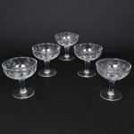 Conjunto de taças para champanhe em meio cristal, diáfano e incolor; bojo hemisférico talhado com flores estilizadas, fuste tubular sobre base circular. Composto de cinco(05) unidades. Medidas: