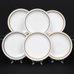 Porcellana Mauá, Mauá - SP(Fundada em 1937 por Fritz Erwin Schmidt / ativa até 1968). Elegante conjunto de pratos rasos em porcelana nacional da década de 1950/60; esmaltação branca, orla circundada por faixa com padrão de meandro grego, entre frisos em douradura contornando a borda e o centro. Marca da manufatura no verso. Composto de cinco(05) unidades. Medida: Diam.: