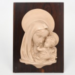 Placa retangular em madeira, com aplicação central em resina moldada em alto-relevo, representando Virgem com o Menino Jesus, ambos com auréolas. Composição frontal, com tratamento volumétrico do grupo e base inferior integrada ao relevo. Parte posterior dotado de gancho para fixação em parede. Estado conforme fotografias. Medidas: