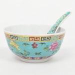 Conjunto com tigela e colher em porcelana chinesa, corpo hemisférico sobre base anelar, acompanhada de colher de cabo alongado; decoração policromada sobre esmalte, apresentando campo externo em tom turquesa, ornamentado com reservas florais e cercadura em meandro grego junto ao bordo. Colher com decoração correlata em arabescos e flor central. Interior em branco. Base com marca em caracteres chineses em vermelho, em cartela geométrica. Medidas: