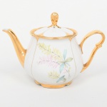 Porcellana Mauá, Mauá - SP(Fundada em 1937 por Fritz Erwin Schmidt / ativa até 1968). Bule para chá em porcelana nacional da década de 1950/60, esmaltação branca, decorada com composição floral em estampagem policromada, bordas, alça lateral, bico vertedor e puxador integralmente recobertos com douradura. Marca da manufatura ao fundo. Medidas: