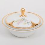 Porcellana Mauá, Mauá - SP(Fundada em 1937 por Fritz Erwin Schmidt / ativa até 1968). Manteigueira em porcelana nacional da década de 1950/60, esmaltação branca, decorada com composição floral em estampagem policromada, bordas e puxador integralmente recobertos com douradura. Marca da manufatura ao fundo. Medidas: