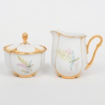 Porcellana Mauá, Mauá - SP(Fundada em 1937 por Fritz Erwin Schmidt / ativa até 1968). Uma(01) leiteira e um(01) açucareiro em porcelana nacional da década de 1950/60, esmaltação branca, decorada com composição floral em estampagem policromada, bordas, alça lateral, bico vertedor e puxador integralmente recobertos com douradura. Marca da manufatura ao fundo. Medidas: