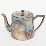 BELPRATA. Elegante bule para chá em metal espessurado à prata, corpo aproximadamente cônico, tampa com abertura basculante, puxador obcônco, bico vertedor curvilíneo, alça lateral curvada encimada por voluta. Marca da manufatura ao fundo. Necesita polimento, e apresenta desgastes no banho de prata. Medidas: