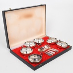 BELLINI. Conjunto de taças para sobremesa em metal espessurado à prata, bojo hemisférico assente sobre três pés esféricos, alça lateral em voluta, acompanha suas respectivas colheres. Acondicionado na caixa, interior revestido em tecido vermelho. Medidas: Alt.:  x Comp.:  x Larg.:  cm.