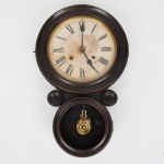 Ansonia Clock Company, Connecticut, EUA(Fundada em 1851 por Anson Green Phelps). Relógio de parede do início do século XX, fabricação estadunidense, modelo "KOBE", ou dito "oito". Caixa circular em madeira, dial de papel sobre chapa metálica, com dois furos de corda indicando mecanismo de corda manual (tempo e batida), numeração romana, ponteiros em metal parte inferior contendo pêndulo em latão dourado. Acompanha chave. Apresenta perda do visor de vidro do pêndulo. Não está funcionando. Medidas: