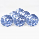 Johnson Brothers, Staffordshire - Inglaterra(Fundada em 1883). Belíssimo conjunto de pratos rasos executado em faiança inglesa, padrão Watermill. Decoração monocromática em azul sob esmalte, representando paisagem rural com moinho hidráulico, executada por estampagem. A composição mostra edifício de moinho com roda dágua em funcionamento, pequeno dique e queda d'água, acompanhados por casas campestres, árvores frondosas, figuras humanas em ambiente bucólico e céu anuviado ao fundo; orla modelada com delicado movimento ondulado, borda recortada com arcos em repetição. Marca da manufatura no verso. Composto de seis(06) unidades. Medida: Diam.: 25 cm.