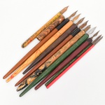 Conjunto composto por exemplares de canetas de pena com cabos de seção cilíndrica, em madeira torneada e material sintético), alguns com decoração marmorizada. Extremidades providas de porta-pena metálico com penas intercambiáveis em aço, de diferentes tipologias. Presença de inscrições e marcas estampadas em algumas penas. Variedade de formatos e dimensões no conjunto. Composto de nove(09) unidades. 