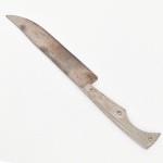 Faca de lâmina em aço com dorso ligeiramente arqueado e ponta aguda, apresentando sinais de forjamento, cabo metálico integral com talas fixadas por rebites, decorado com gravação de motivos geométricos e estilizados. Estado de conservação conforme fotografias, apresentando oxidação, desgaste e marcas de uso. Medida: