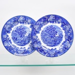 Wood & Sons, Burslem - Inglaterra(Fundada em 1865). Dois(02) pratos rasos em faiança inglesa da década de 1920. Esmaltagem vítrea na cor branca, profusa decoração intitulada 'English Scenery' obtida por transferência( transfer printing), contendo paisagem campestre contendo casario, árvores, carruagem, personagens e igreja ao fundo, orla circundada por flores e folhagens, borda contornada por friso na tonalidade cobalto. Marca da manufatura no verso. Medida.: Diâmetro: 25,5 cm