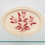 S.I.C. (Scuola Italiana Ceramica), Casale Monferrato - Itália. Elegante travessa oval em majólica italiana da década de 1950/60; esmaltação vítrea de tonalidade creme, centro ligeiramente rebaixado, decorado com composição botânica manual em tom bordô, orla circundada por friso relevado na própria pasta. Marca da manufatura no verso. Medidas: