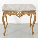 Mesa lateral em madeira entalhada e dourada, estilo Louis XV / Rococó, com tampo em mármore de contorno recortado, com bordas boleadas. Saia recortada e vazada, com elementos decorativos em motivo concheado e fitomorfo, intercalados por treliças geométricas. Apoio sobre quatro pernas cabriolet, com joelhos entalhados e terminação em pés recurvos. Medidas: Alt.: 51 x Comp.: 64 x Larg.: 47 cm.