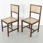 Par de cadeiras construídas em madeira, modelo Cane Chairs, produzidas por M.L. Magalhães na década de 1960, com espaldar retangular e assento em palhinha natural tramada. Estrutura de linhas retas, com pernas de seção quadrangular, unidas por travessas horizontais de reforço. Espaldar com moldura simples, encaixando painel de palhinha. Medidas: Alt.: 89,5 x Comp.: 42,5 x Larg.: 42 cm.
