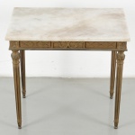 Mesa de canto em madeira entalhada e dourada, de estilo neoclássico, com tampo retangular em mármore. Saia decorada com frisos geométricos e cartela central com motivos vegetalistas em relevo. Sustentação por quatro pernas torneadas, com caneluras verticais e elementos ornamentais na transição para a cintura. Medidas: Alt.: 54 x Comp.: 59,5 x Larg.: 40 cm.