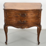 Mesa de cabeceira em madeira entalhada e dourada, de estilo Luís XV, com tampo recortado de contorno sinuoso, dotado duas gavetas frontais sobrepostas, de frente ondulada, ornadas por molduras em relevo e puxadores metálicos de desenho rocaille. Saial recortado com composição entalhada central de volutas e motivos vegetalistas. Laterais levemente abauladas. Sustentada por quatro pernas cabriolet, com joelhos ornados por reservas florais e terminação com pés de enrolamento. Medidas: Alt.: 60 x Comp.: 62 x Larg.: 38 cm.