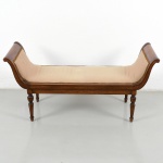 Canapé construído em madeira, estilo neoclássico, com estrutura retangular, assento estofado contínuo e extremidades elevadas em volutas opostas, formando encostos laterais integrados.Estrutura com travessas retas, sustentada por quatro pernas torneadas com elementos em balaústre. Assento e encostos laterais estofados, revestidos em tecido, com acabamento perimetral por galão aplicado. Medidas: Alt.: 64 x Comp.: 132 x Larg.: 44,5 cm.