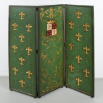 Biombo de três folhas construído em madeira, com painéis retangulares articulados por dobradiças metálicas. Cada folha apresenta fundo pintado em tonalidade verde, delimitado por moldura perimetral lisa. Faces frontais ornamentadas com aplicações em relevo de flor-de-lis rematada com generoso douramento, distribuídas de maneira regular, intercaladas por pequenos elementos circulares também em relevo; folha central apresenta composição decorativa diferenciada, com pintura de arabescos vegetalistas em dourado, centralizando escudo heráldico em relevo, encimado por coroa, escudo quartelado, com campos em vermelho e branco, ornados por flor-de-lis e elementos pontuais em relevo. Estado de conservação conforme fotografias. Medidas: Alt.: 168 x Comp.: 162 cm.