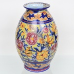 Grande vaso em cerâmica portuguesa, fabricação da região de Alcobaça, corpo bojudo ricamente ornamentado com composição floral em policromia, com flores de tonalidades rosa e amarelo, folhagens em azul, faixas com elementos geométricos, e fundo de tom cobalto. Apresenta acentuada rachadura, demanda restauro. Marca indicativa de produção da região de Alcobaça ao fundo. Medidas: