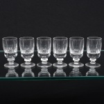 Conjunto composto por seis(06) cálices em cristal incolor, apresentando bojo cilíndrico levemente abaulado, apoiado sobre haste curta com nó central e base circular, bojos decorados com lapidação geométrica composta por facetas verticais alongadas e cortes lineares. Medidas: Alt.: x Diam.: