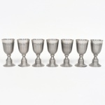 Conjunto de cálices confeccionados em estanho, bojo oval, fuste afunilado sobre base campaniforme. Produção nacional da região de MG. Composto de sete(07) unidades. Medidas: