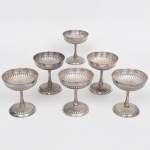 EBERLE. Conjunto de taças de pé alto para sobremesa, confeccionadas em metal espessurado à prata, bojo hemisférico repuxado com sucessão de gomos verticais, haste afunilada sobre base ligeiramente abaulada. Composto de seis(06) unidades. Necessita polimento e/ou refazer banho de prata. Medidas: