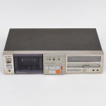 Deck de fita cassete estéreo, marca Sony, modelo TC-FX5BS, fabricado no Brasil sob licença da Sony Corporation, Japão. Gabinete metálico com painel frontal em acabamento escovado, compartimento frontal para fita com visor translúcido, contador mecânico de fita e comandos de operação por teclas. Painel equipado com medidor de nível (peak program meter) para canais esquerdo e direito, controle deslizante de nível de gravação, seleção de tipo de fita (Type I, II, III e IV) e sistema de redução de ruído Dolby NR com acionamento manual. Entradas frontais para microfone (L/R) e saída para fones de ouvido. Parte traseira com conexões de entrada e saída de linha (RCA), seletor de voltagem e cabo de alimentação fixo. Alimentação elétrica: AC 110120V / 220240V, 50/60Hz, 22W. Identificação de fábrica com número de série presente. Estado de conservação com sinais de uso, oxidação superficial no tampo superior e marcas de manuseio. Não foi testada, sem garantias de funcionamento.