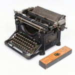 Máquina de escrever mecânica de mesa, marca Underwood, produzida pela Underwood Elliott Fisher Co., Estados Unidos, datável do início do século XX, circa 19101925. Estrutura em metal fundido com acabamento em pintura de tonalidade preta, teclado alfanumérico com teclas circulares e hastes metálicas, carro móvel com rolete (platen) em borracha e sistema de retorno manual por alavanca lateral. Equipada com régua de margem graduada, seletores de avanço, suporte para fita entintada bicolor e mecanismo de impressão por barras de tipos convergentes. Identificação do fabricante e inscrições de patente aplicadas na parte posterior.Acompanha acessório em caixa identificado como Cleaning Outfit Typewriter, destinado à manutenção do equipamento, neste exemplar contendo apenas a escova(vide foto).Estado de conservação conforme fotografias, não foi testada, sem garantias de funcionamento.