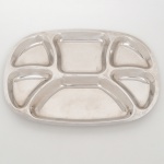 Petisqueira em metal prateado, de formato oval, corpo inteiriço com cavidades moldadas e rebaixadas formando compartimentos distintos, dispostos de maneira radial e central. Medidas: