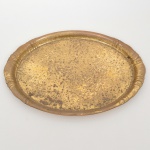 Bandeja oval confeccionada em metal amarelo, centro ligeiramente rebaixado, borda revirada para fora, repuxada com sulcos verticais. Necessita refazer banho, apresenta sinais de oxidação. Medidas: