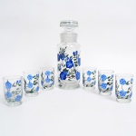 Conjunto para licor em vidro incolor esmaltado, composto por garrafa com rolha esmerilhada e seis copos, em vidro incolor, com decoração em esmalte policromo representando ramos florais com flores estilizadas em tonalidade azul e folhagem verde. Corpos cilíndricos, base espessada integrada; garrafa com ombros suaves e gargalo com encaixe esmerilhado. Medidas: