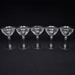 Belíssimo conjunto de taças de pé alto, para champanhe, executado em cristal europeu, diáfano e incolor; bojo campaniforme, borda ligeiramente evertida, gravado com flores e faixa contínua de motivo vegetalista , haste tubular com anel intermediário e base circular. Composto de cinco(05) unidades. Medidas: Alt.: x Diam.:
