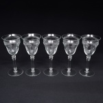Belíssimo conjunto de taças de pé alto, para ....., executado em cristal europeu, diáfano e incolor; bojo obcônico, borda ligeiramente evertida, gravado com flores e faixa contínua de motivo vegetalista , haste tubular com anel intermediário e base circular. Composto de cinco(05) unidades. Medidas: Alt.: x Diam.:
