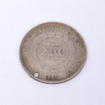NUMISMÁTICA. Moeda do Período Imperial Brasileiro, valor de face 500 Réis, II FAMÍLIA, 2 tipo 1853 - 1867, bordo serrilhado, executada em prata 917 milésimos. Reverso apresenta brasão imperial encimado pela inscrição IN HOC SIGNO VINCES; Anverso valor de face circundado pela inscrição PETRUS II.D.G.CONST.IMP.ET PERP.BRAS.DEF. Med.: Diam. 2,5 cm. Apresenta perfuração junto ao bordo.