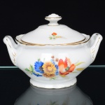 Springer & Co, EPIAG - Checoslováquia(Fundada entre 1918 e 1920 a partir de fábricas nos arredores de Carlsbad). Excepcional açucareiro em porcelana tcheca da década de 1920. Esmaltagem vítrea na cor branca, corpo bojudo assentado sobre base circular moldada com movimento ondulatório, orlas circundadas por faixa contendo frisos e enrolamentos relevados na própria pasta; faces decoradas com bela composição botânica em estampagem policromada, predominando as tonalidades amarelo, ocre, azul, coral, verde e marsala; contornos ornamentados com aplicação de filetes em douradura; tampa ligeiramente abaulada encimada por puxador com feitio de pião, alça laterais reviradas para cima. Marca da manufatura no verso. Medidas: Alt.: 11 x Comp.: 15,5 x Larg.: 12,5 cm. (A Springer & Co de Elbogen na Boêmia foi formada na década de 1880 e encerrou suas atividades em 1945. Ela foi uma das fábricas fundadoras originais da OEPIAG (mais tarde EPIAG), que era uma associação de olarias formadas pelo governo de Viena em 1918 para promover a venda de cerâmica e porcelana da Boêmia. Foi inicialmente denominado OEPIAG, um acrônimo para Österreichische Porzellan Industrie AG ou Austrian Porcelain Industry, mas foi alterado para EPIAG - Erste Böhemische Porzellan Industrie AG que significa Primeira Indústria de Porcelana da Boêmia - em 1920 após a independência da Checoslováquia).